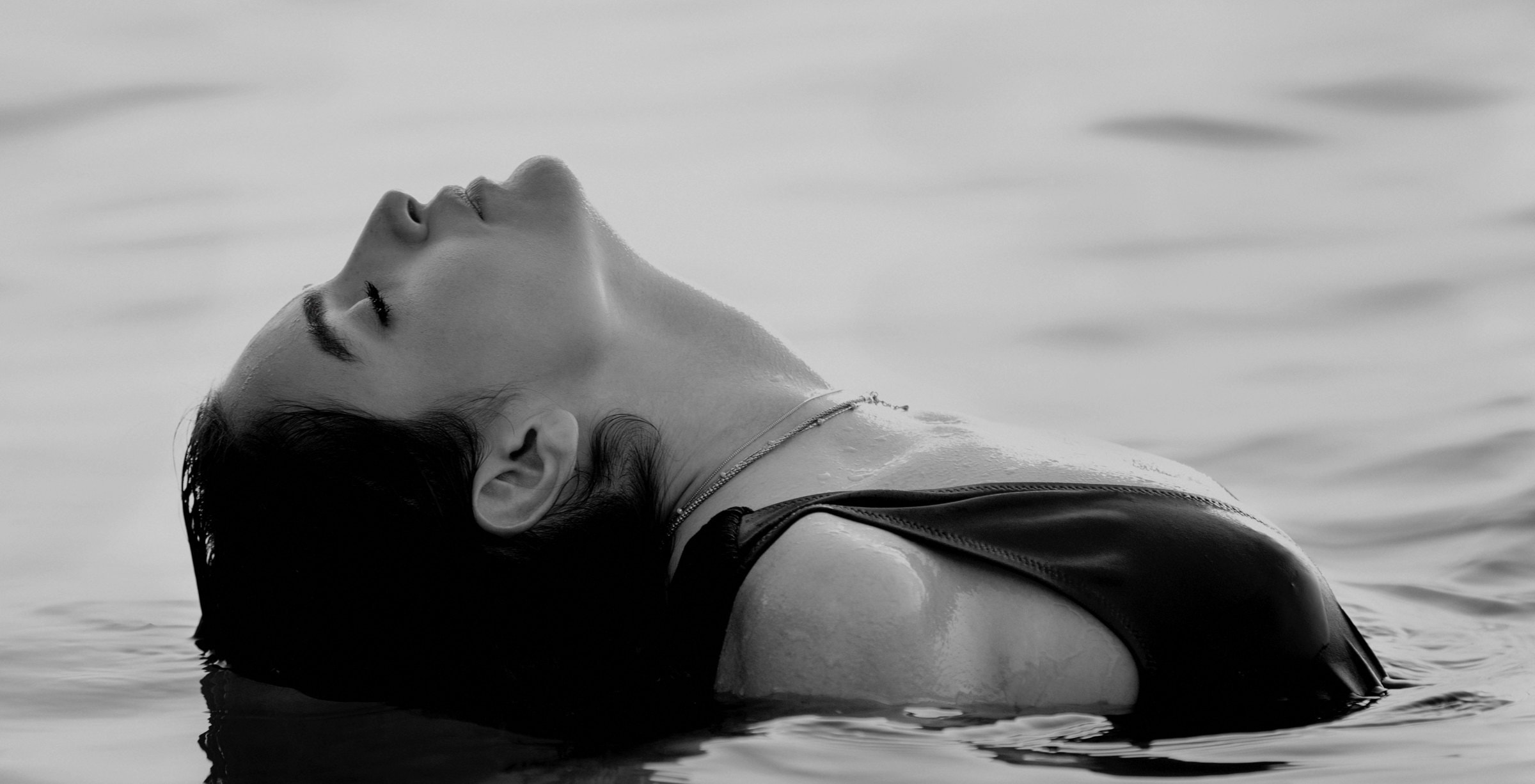 A woman floating face-up and at rest on the surface of still water